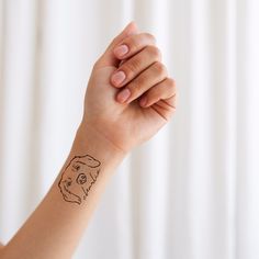 a woman's arm with a small dog tattoo on the left side of her wrist