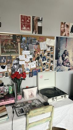 a table with a record player, flowers and pictures on the wall