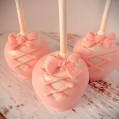 three pink cake pops with bows on them