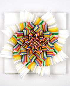 an art piece made out of strips of colored paper on top of a white surface