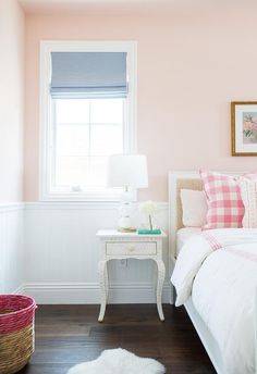 a bedroom with pink walls and white furniture