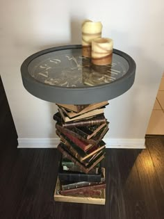 a stack of books sitting on top of a table next to a vase and candle