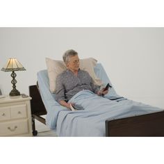 an older woman laying in bed with a remote control