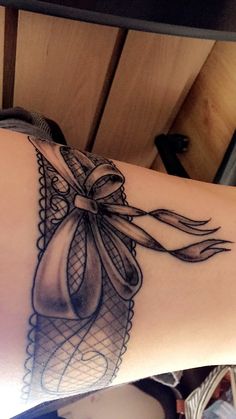 a woman's arm with a bow and lace tattoo design on the left side