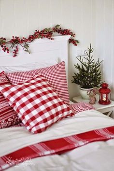 a bed with red and white checkered pillows on top of it next to a christmas tree