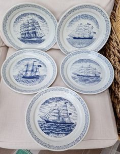 four blue and white plates sitting on top of a table next to a wicker basket