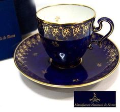 a blue cup and saucer sitting on top of a white table next to a box