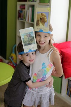 two young children standing next to each other in a room with books on their heads