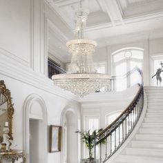 a large white staircase with chandelier and mirror on the wall next to it