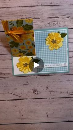 a card with yellow flowers on it sitting on top of a wooden table next to a piece of paper