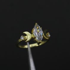 a gold ring with an oval cut diamond and two smaller round diamonds on the side