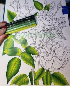 a person is drawing flowers on a sheet of paper with colored pencils and markers