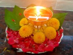 a lit candle sitting on top of a bowl filled with flowers