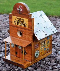 a wooden birdhouse with a metal roof and sign on the top that says general store