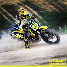 a man riding on the back of a yellow motorcycle down a dirt covered road with trees in the background