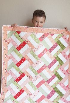 a young boy is holding up a quilt