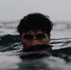 a man swimming in the ocean with his head above the water's surface looking at the camera