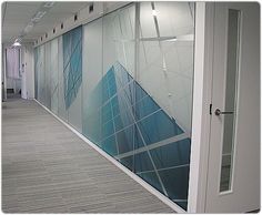 an office hallway with blue and white glass panels on the wall, along with a door leading to another room