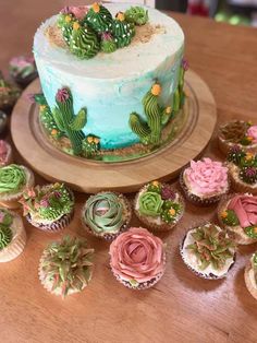 a cake and cupcakes are arranged on a table with cactus decorations around it