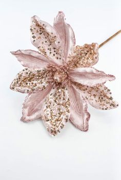 a pink flower with gold sequins on it's petals is sitting on a white surface