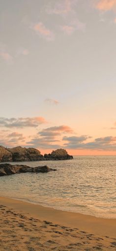 two people walking on the beach at sunset