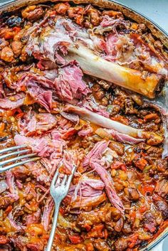 a large pot filled with meat and vegetables on top of a table next to a fork