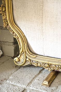 a gold framed mirror sitting on top of a brick floor next to a white wall