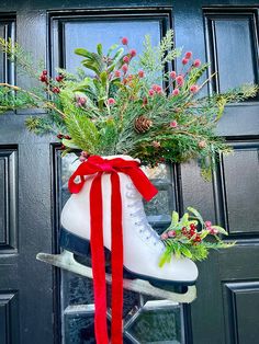 a pair of ice skates decorated with greenery and red ribbon hanging from the front door