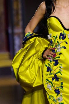 a woman in a yellow dress with flowers on it's chest and handbag