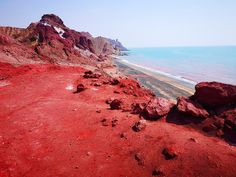 red sand and rocks near the ocean on a sunny day