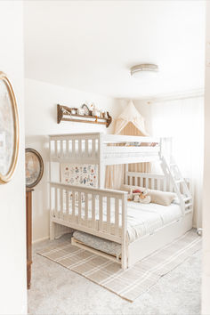 A white twin over full bunk bed with a ladder and trundle are shown in a room with a princess feel. This little girls room is white, beige, and neutral. There is a shelf on the wall and a rug under the bed. Full And Twin Bed Shared Room Bedroom Ideas, Boy Girl Bunk Beds Shared Bedrooms, Boy And Girl Bunk Beds Shared Bedroom, Shared Bedroom Ideas Boy And Girl, Boy And Girl Shared Bedroom Bunk Beds, Bunk Bed Girls Room, Cozy Nyc Apartment, Girls Room Bunk Beds, Ivy Bedroom