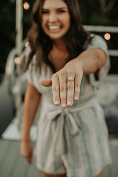 a woman pointing at the camera with her hand on her hip and wearing a ring