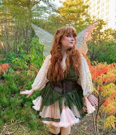 a woman dressed as a fairy standing in the grass