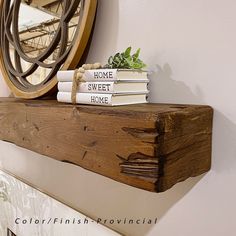 some books are sitting on top of a wooden shelf next to a clock and mirror