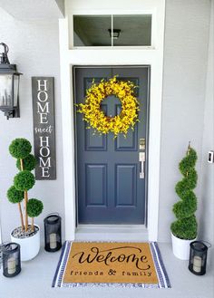 a blue front door with a welcome mat and potted plants