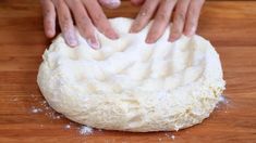 someone kneading dough on top of a wooden table