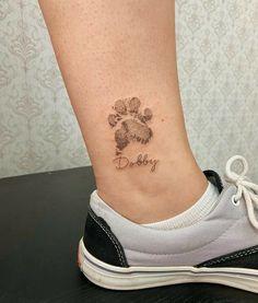 a small tattoo on the ankle of a woman's foot with a dog paw