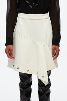 A deconstructed take on utilitarian styles, this A-line mini skirt is crafted from cotton twill and falls to an asymmetric hem. A row of polished silver-tone eyelets frames the silhouette. Cotton twill High waist Asymmetric mini-length hem with eyelet embellishment Silver-tone metal hardware Concealed zip back fastenin Modern Skirt With Asymmetrical Hem For Spring, Modern Asymmetrical Hem Skirt For Spring, Cotton Asymmetrical Mini Skirt, Chic Asymmetrical Cotton Skirt, Knit Swimwear, Utility Skirt, Eyelet Skirt, Utilitarian Style, Ecru Color