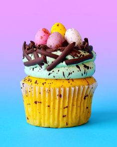 a cupcake with chocolate sprinkles and eggs on top, sitting on a blue surface