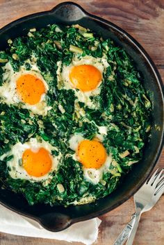 three eggs are in a skillet with spinach