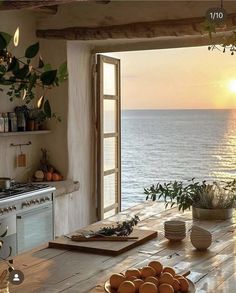 a kitchen with an open window overlooking the ocean at sunset or sun set over the water