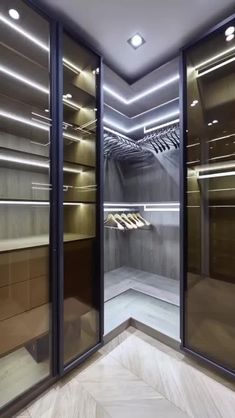 an empty walk in closet with glass doors and lights on the ceiling is lit by recessed lighting