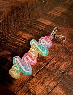 a keychain with the word hope written in rainbow colors on it sitting on a wooden surface