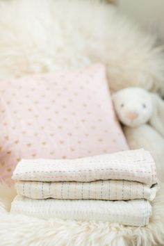 a pile of blankets sitting on top of a bed next to a stuffed animal toy