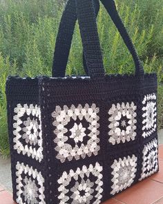 a black and white crocheted bag sitting on the ground