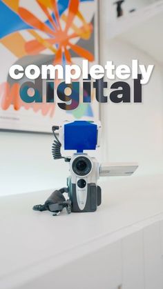 a camera sitting on top of a white counter next to a wall with the words completely digital