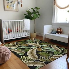 a baby's room with a white crib, black and green rug, potted plant and wooden floor