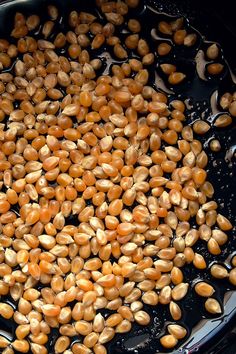 corn kernels are being cooked in a black pan on the stove top with water