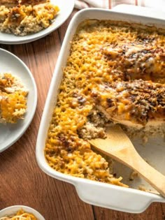 a casserole dish with cheese and meat in it next to two plates on the table