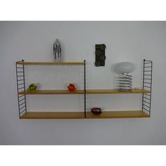 two wooden shelves with wire baskets and utensils on them against a white wall